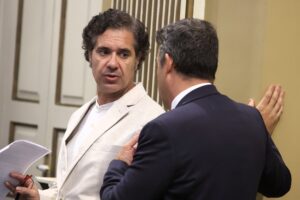 El portavoz adjunto del Grupo Parlamentario Agrupación Socialista, Jesús Ramos, dialoga con otro diputado en el Salón de Plenos de la Cámara autonómica.